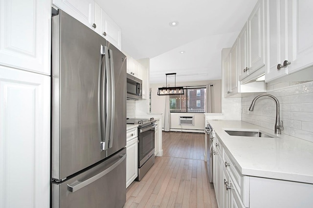 107 N Broadway Unit 201, White Plains, NY 10603 - kitchen featuring stainless steel appliances, a sink, white cabinets, light wood-style flooring, and backsplash