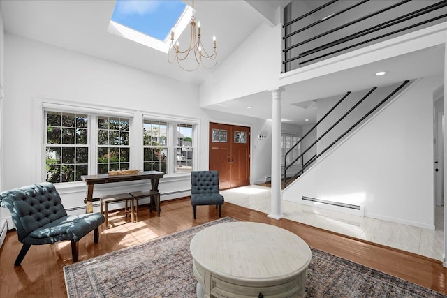 18 Stirrup Ln, Glen Cove, NY 11542 - foyer featuring baseboard heating, ornate columns, wood finished floors, a skylight, and a chandelier