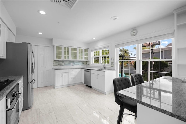 18 Stirrup Ln, Glen Cove, NY 11542 - kitchen featuring black appliances, stone counters, recessed lighting, glass insert cabinets, and white cabinets