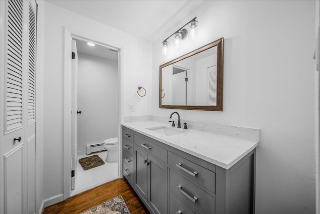 18 Stirrup Ln, Glen Cove, NY 11542 - bathroom with baseboard heating, vanity, wood finished floors, a closet, and toilet