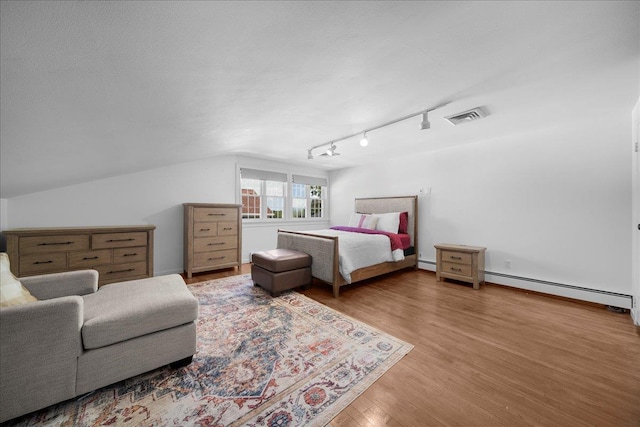 18 Stirrup Ln, Glen Cove, NY 11542 - bedroom with baseboard heating, wood finished floors, and rail lighting