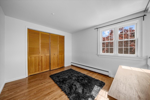 18 Stirrup Ln, Glen Cove, NY 11542 - unfurnished bedroom with a baseboard radiator, light wood-style flooring, and baseboards