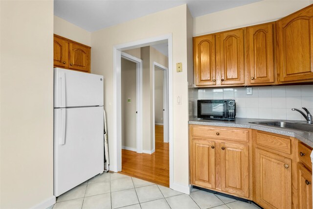 11 Parsons St, Harrison, NY 10528 - kitchen featuring freestanding refrigerator, black microwave, brown cabinets, a sink, and light tile patterned floors