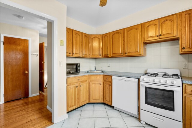 11 Parsons St, Harrison, NY 10528 - kitchen with white appliances, a sink, tasteful backsplash, brown cabinetry, and light wood finished floors