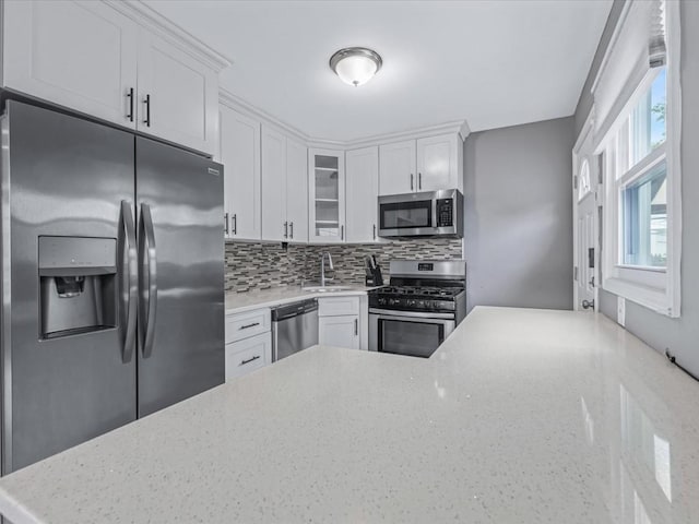251 Woods Rd, North Babylon, NY 11703 - kitchen featuring stainless steel appliances, a sink, tasteful backsplash, glass insert cabinets, and white cabinets