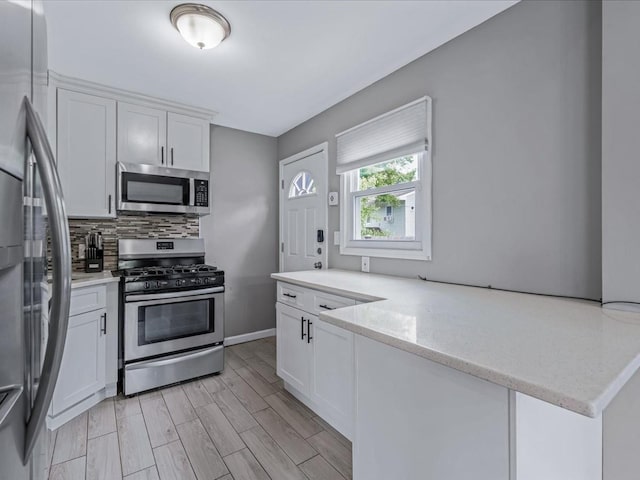 251 Woods Rd, North Babylon, NY 11703 - kitchen featuring stainless steel appliances, tasteful backsplash, white cabinets, light wood-style floors, and light stone counters