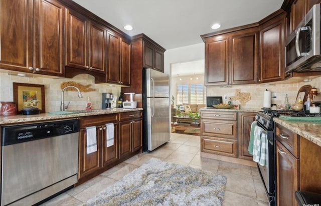 56 Yacht Club Rd, Babylon, NY 11702 - kitchen with appliances with stainless steel finishes, decorative backsplash, light stone countertops, light tile patterned floors, and recessed lighting