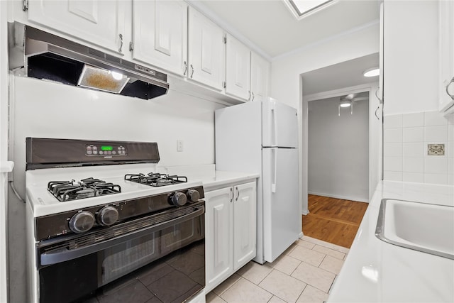 415 Gramatan Ave Unit 2C, Mount Vernon, NY 10552 - kitchen with gas range oven, under cabinet range hood, freestanding refrigerator, white cabinets, and light countertops