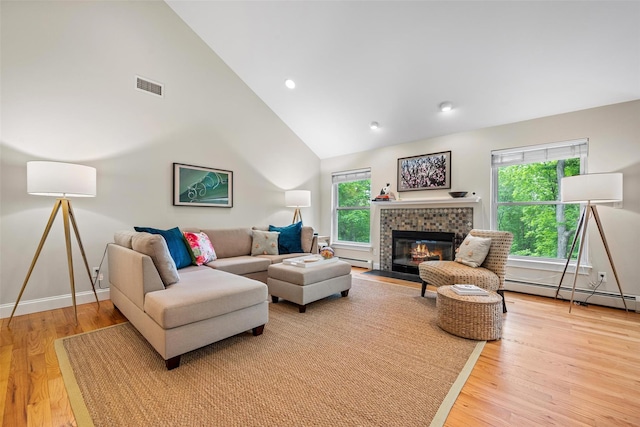 72 Greencrest Rd, Goshen, NY 10924 - living area featuring light wood-style flooring, a baseboard radiator, high vaulted ceiling, a tiled fireplace, and baseboards