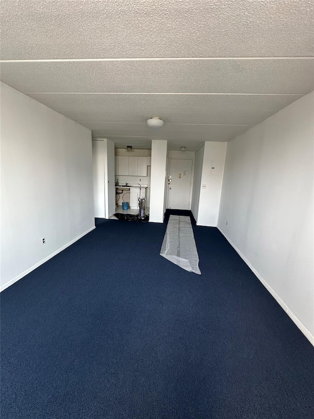 97-12 63rd Dr Unit 10D, Rego Park, NY 11374 - unfurnished living room featuring a textured ceiling and dark carpet