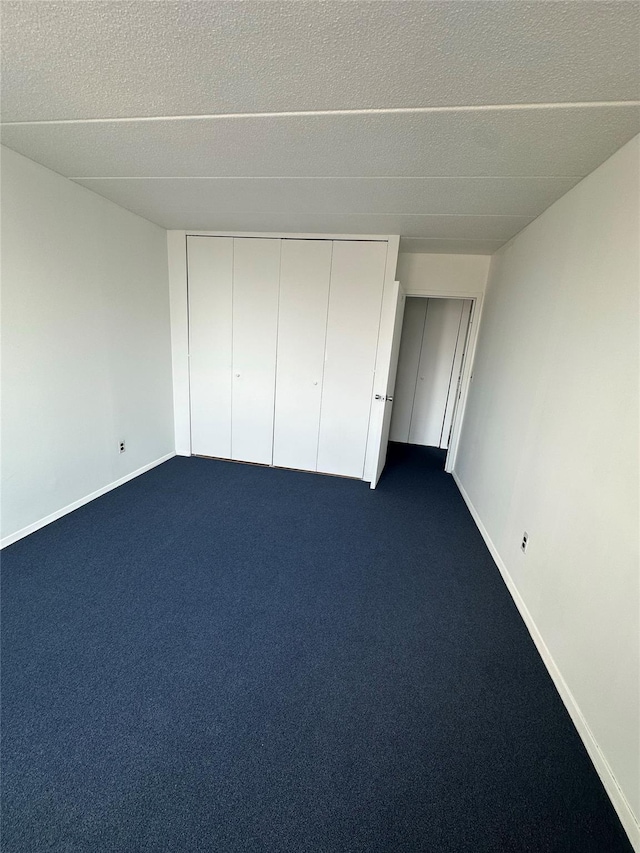 97-12 63rd Dr Unit 10D, Rego Park, NY 11374 - unfurnished bedroom with a textured ceiling, dark carpet, and a closet