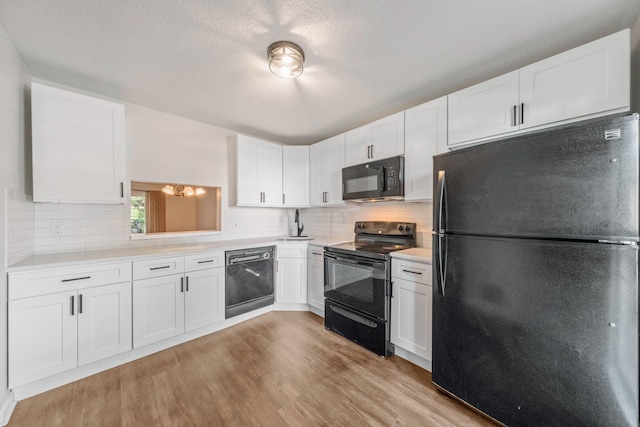 8 Moore Ln, Washingtonville, NY 10992 - kitchen featuring black appliances, light countertops, light wood-type flooring, white cabinets, and a textured ceiling