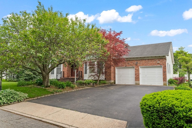 14 Battle Row, Old Bethpage, NY 11804 - view of property hidden behind natural elements featuring driveway, a garage, brick siding, and roof with shingles