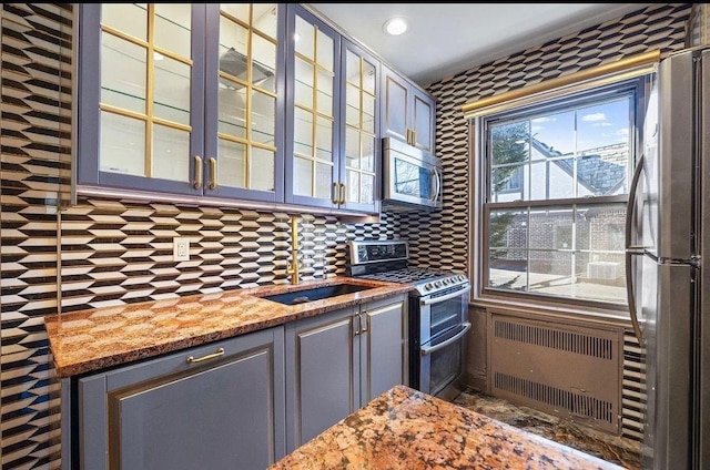 255 Central Ave Unit 202-A, Lawrence, NY 11559 - kitchen featuring stainless steel appliances, radiator, decorative backsplash, glass insert cabinets, and light stone counters
