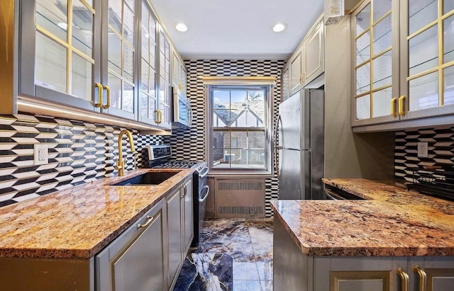 255 Central Ave Unit 202-A, Lawrence, NY 11559 - kitchen featuring stainless steel appliances, radiator, decorative backsplash, light stone countertops, and recessed lighting
