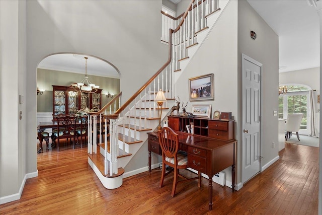 40 Carlisle Ln, East Islip, NY 11730 - staircase featuring a chandelier, wood finished floors, arched walkways, ornamental molding, and a high ceiling