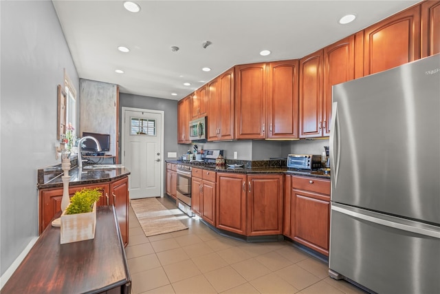 64 Chester Rd, Lynbrook, NY 11563 - kitchen featuring appliances with stainless steel finishes, recessed lighting, dark stone counters, light tile patterned flooring, and brown cabinets
