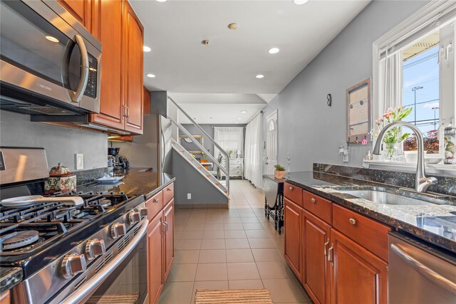 64 Chester Rd, Lynbrook, NY 11563 - kitchen featuring appliances with stainless steel finishes, a sink, dark stone counters, light tile patterned flooring, and brown cabinets