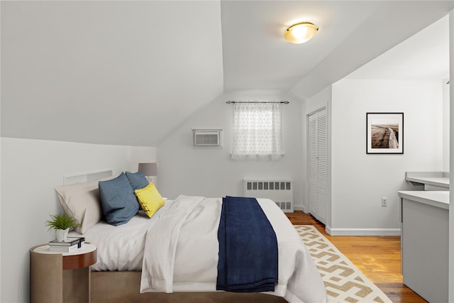 64 Chester Rd, Lynbrook, NY 11563 - bedroom featuring radiator heating unit, wood finished floors, lofted ceiling, a wall mounted AC, and a closet