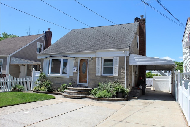 386 Locust Ave, Uniondale, NY 11553 - bungalow featuring roof with shingles, concrete driveway, a chimney, and a gate