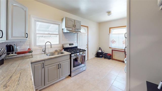 386 Locust Ave, Uniondale, NY 11553 - kitchen with gas range, under cabinet range hood, a sink, backsplash, and light stone countertops