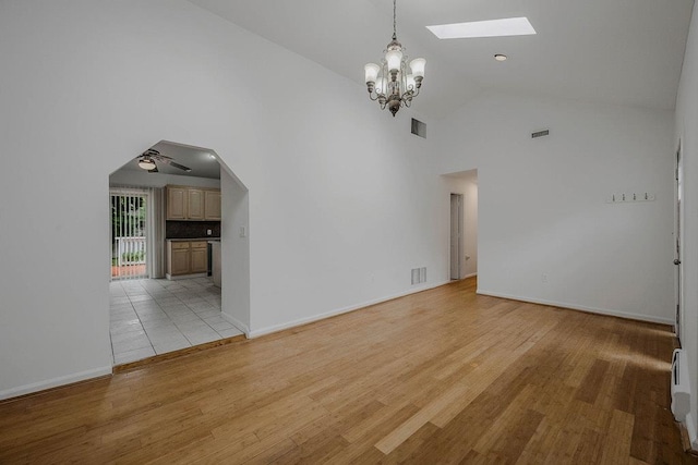 5 Charles St, Selden, NY 11784 - unfurnished living room featuring a skylight, a chandelier, high vaulted ceiling, light wood-style flooring, and baseboards