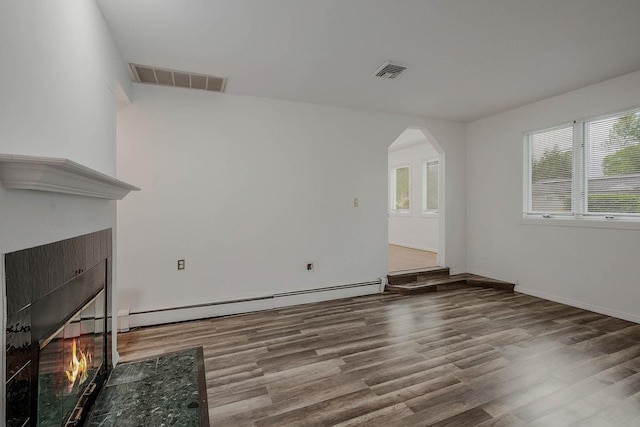 5 Charles St, Selden, NY 11784 - unfurnished living room featuring a tile fireplace, a baseboard heating unit, wood finished floors, and arched walkways