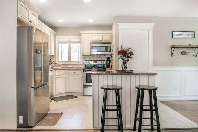 110 Sound Beach Blvd, Sound Beach, NY 11789 - kitchen with appliances with stainless steel finishes, a breakfast bar area, a center island, decorative backsplash, and dark stone countertops