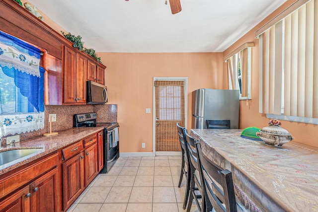 11 Whaley St, Freeport, NY 11520 - kitchen with appliances with stainless steel finishes, a sink, baseboards, stone counters, and light tile patterned flooring