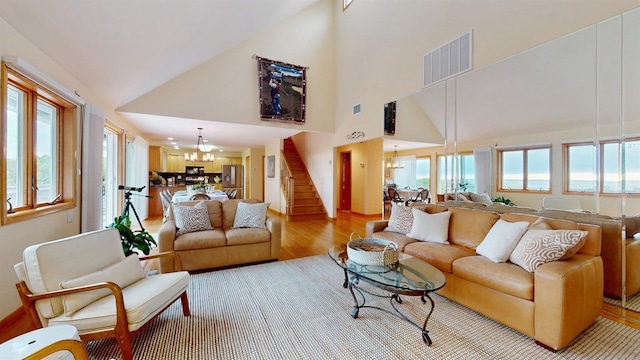 70 Jean Ct, Riverhead, NY 11901 - living room with a chandelier, light wood-style floors, high vaulted ceiling, and stairway