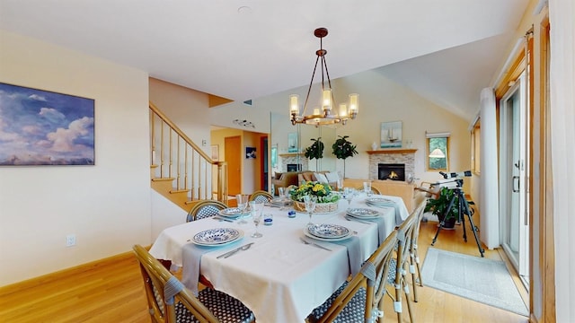 70 Jean Ct, Riverhead, NY 11901 - dining space with light wood finished floors, a chandelier, a warm lit fireplace, stairs, and vaulted ceiling