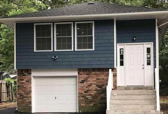 28 Ozark St, Ronkonkoma, NY 11779 - view of front facade with brick siding and a garage