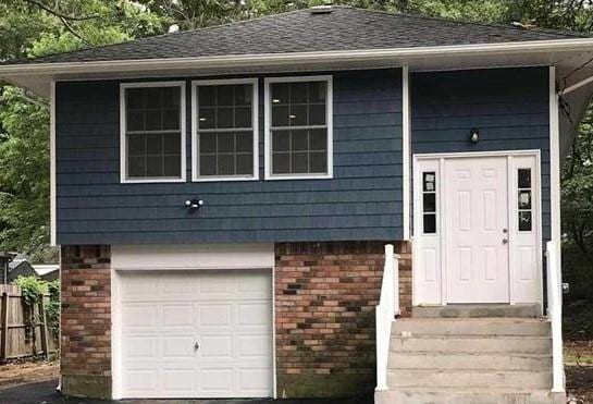 28 Ozark St, Ronkonkoma, NY 11779 - view of front facade with brick siding and a garage