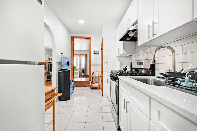 113-23 204th St, Saint Albans, NY 11412 - kitchen with freestanding refrigerator, gas stove, under cabinet range hood, decorative backsplash, and white cabinets