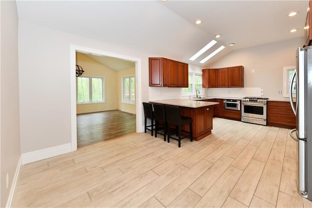 11 Brookview Blvd, Chestnut Ridge, NY 10977 - kitchen featuring appliances with stainless steel finishes, vaulted ceiling, light wood-style floors, a peninsula, and a sink