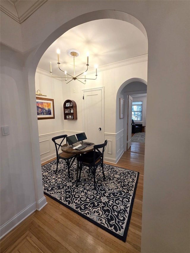117-01 Park Ln S Unit A3C, Kew Gardens, NY 11415 - dining area featuring crown molding, wood finished floors, arched walkways, a chandelier, and a decorative wall