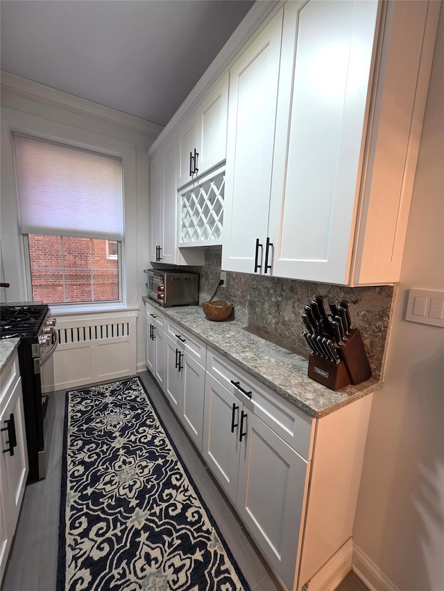 117-01 Park Ln S Unit A3C, Kew Gardens, NY 11415 - kitchen featuring stainless steel gas range oven, white cabinets, light stone countertops, dark wood finished floors, and tasteful backsplash