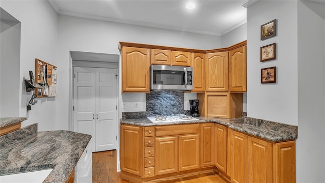 110 Driscoll Ave, Rockville Centre, NY 11570 - kitchen featuring stainless steel microwave, white gas cooktop, crown molding, light wood-style flooring, and decorative backsplash