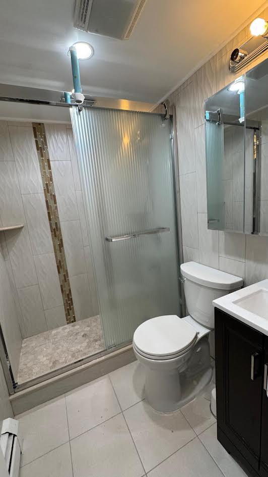 15307 79th Ave, Flushing, NY 11367 - full bathroom featuring vanity, a stall shower, tile patterned flooring, toilet, and tile walls