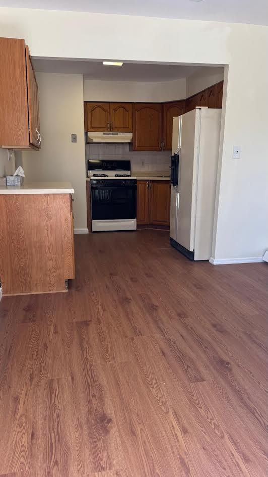 15307 79th Ave, Flushing, NY 11367 - kitchen featuring white appliances, under cabinet range hood, baseboards, and dark wood-style floors