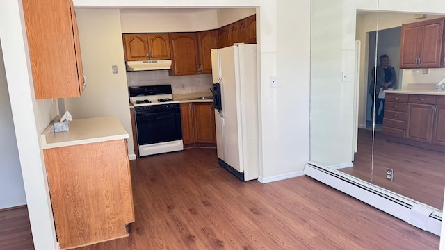 15307 79th Ave, Flushing, NY 11367 - kitchen with white appliances, under cabinet range hood, a baseboard radiator, and dark wood finished floors