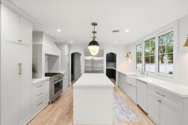 14 Kennedy Ln, West Islip, NY 11795 - kitchen with premium appliances, arched walkways, a sink, a kitchen island, and light wood-style floors
