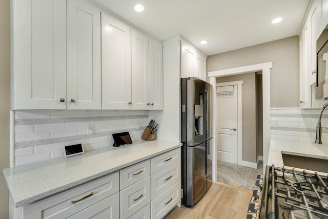 460 Old Town Rd Unit 25N, Port Jefferson Station, NY 11776 - kitchen featuring stainless steel refrigerator with ice dispenser, backsplash, white cabinets, light stone countertops, and light wood-type flooring