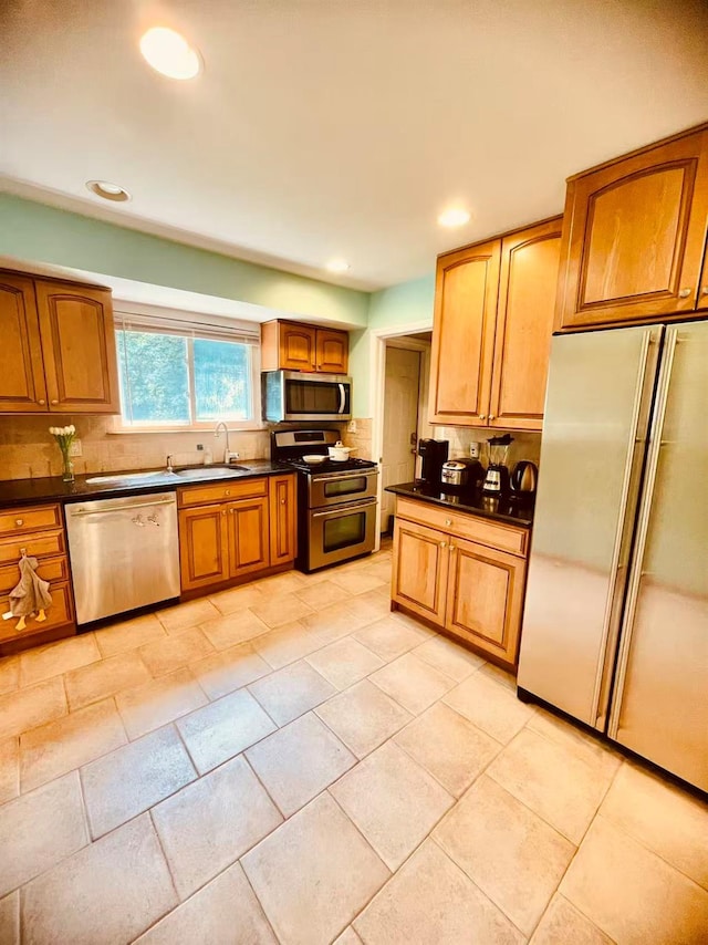 663 Woodbury Rd, Oyster Bay, NY 11791 - kitchen featuring appliances with stainless steel finishes, dark countertops, a sink, tasteful backsplash, and brown cabinets