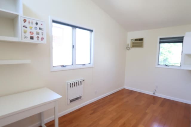 22-23 147th St, Whitestone, NY 11357 - interior space featuring radiator, a wall mounted air conditioner, light wood-style flooring, and baseboards