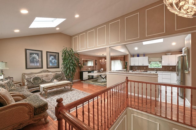 6 Country Ct, Farmingdale, NY 11735 - living area with a chandelier, wood finished floors, a skylight, vaulted ceiling, and recessed lighting