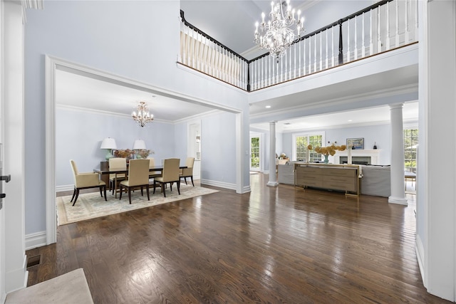 47 Valley Rd, Old Westbury, NY 11568 - dining room with decorative columns, a chandelier, wood finished floors, a towering ceiling, and crown molding