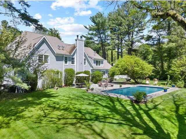 47 Valley Rd, Old Westbury, NY 11568 - rear view of house with a chimney, an outdoor pool, a patio area, and a lawn
