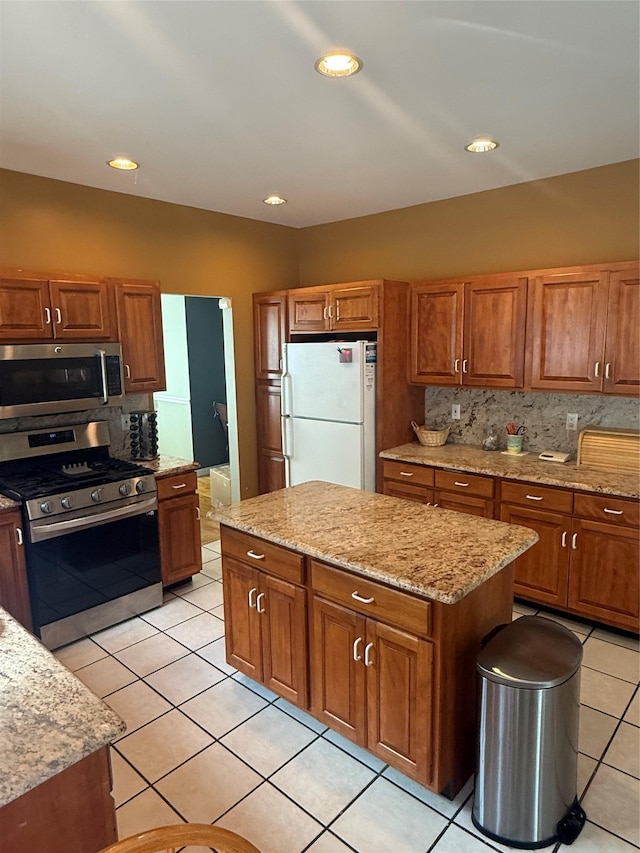 12 Rosell Ct, Lagrangeville, NY 12540 - kitchen with appliances with stainless steel finishes, light tile patterned floors, brown cabinetry, light stone counters, and recessed lighting
