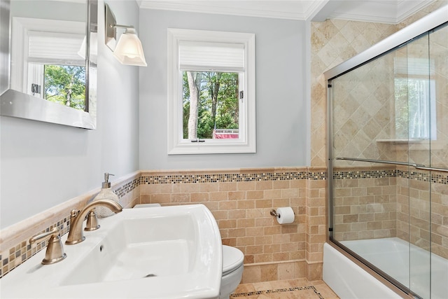 2360 Marlene Ln, Mattituck, NY 11952 - bathroom featuring tile walls, toilet, ornamental molding, a sink, and bath / shower combo with glass door